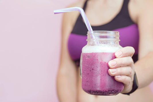 Female athlete holding grape-flavored nootropic supplement drink